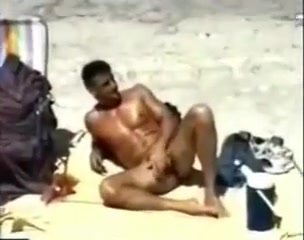 Wanking his huge cock on the beach